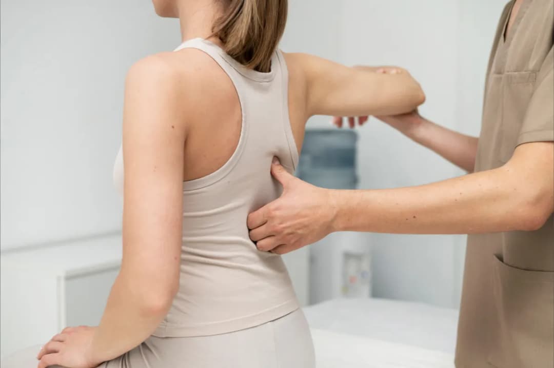 Physiotherapist assessing a patient's lower back during a home visit