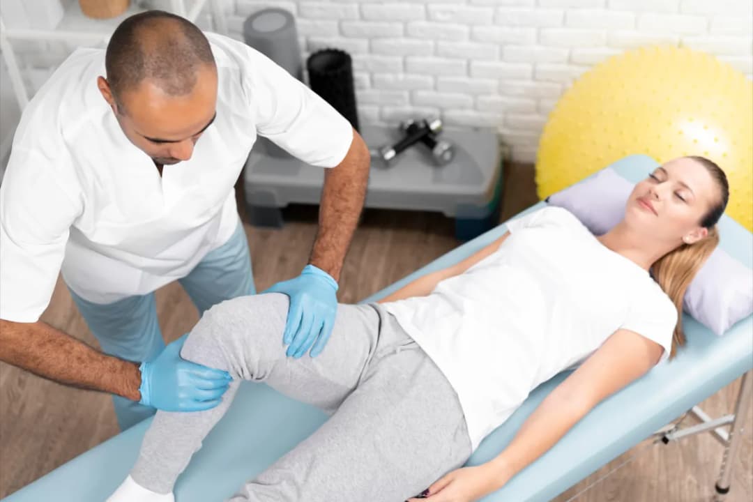 Physiotherapist assessing a patient's knee during a home visit