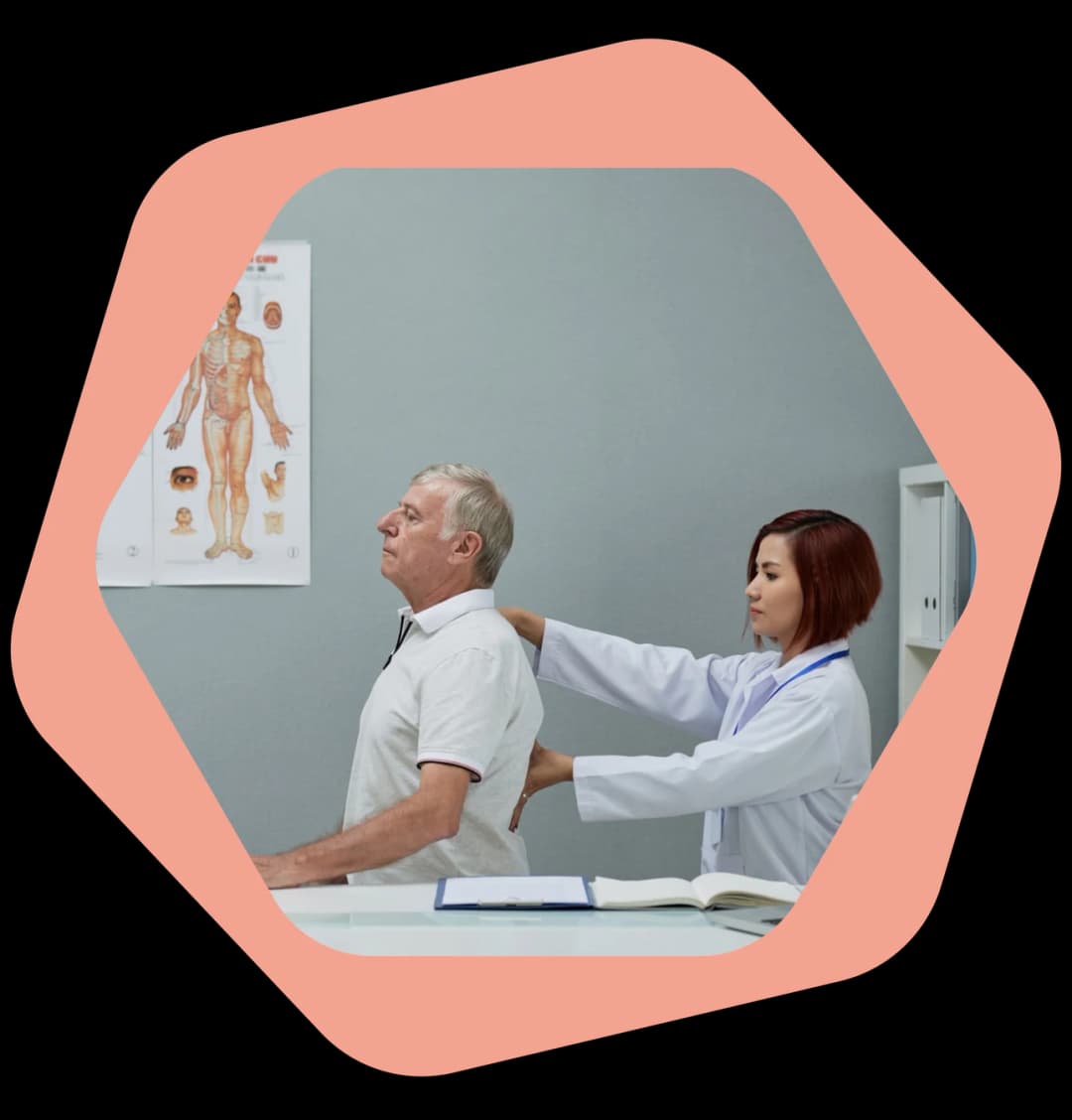 Physiotherapist assessing a patient's lower back during a home visit