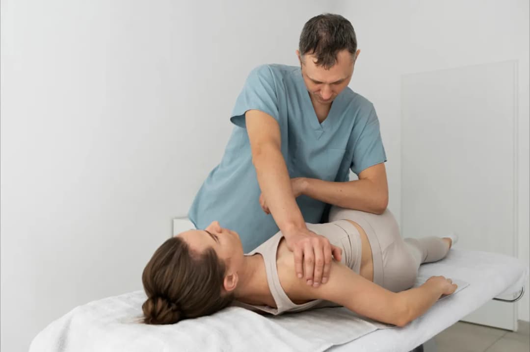 Physiotherapist guiding a patient through sciatic nerve glides during a home visit